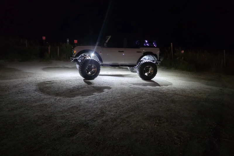 Ford Bronco lit by white Axion RGB+W rock lights at night.