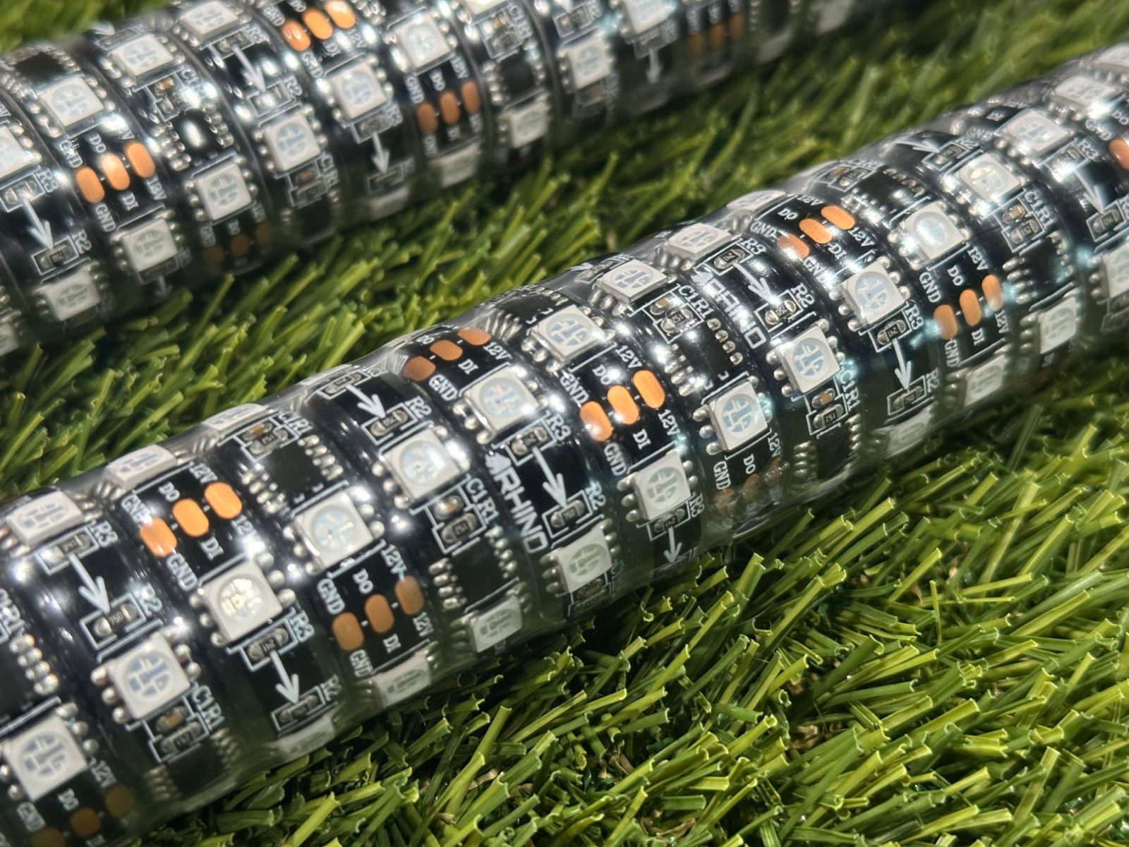 Macro of two wrapped whips on turf, close enough to read the strip, with no gap between runs