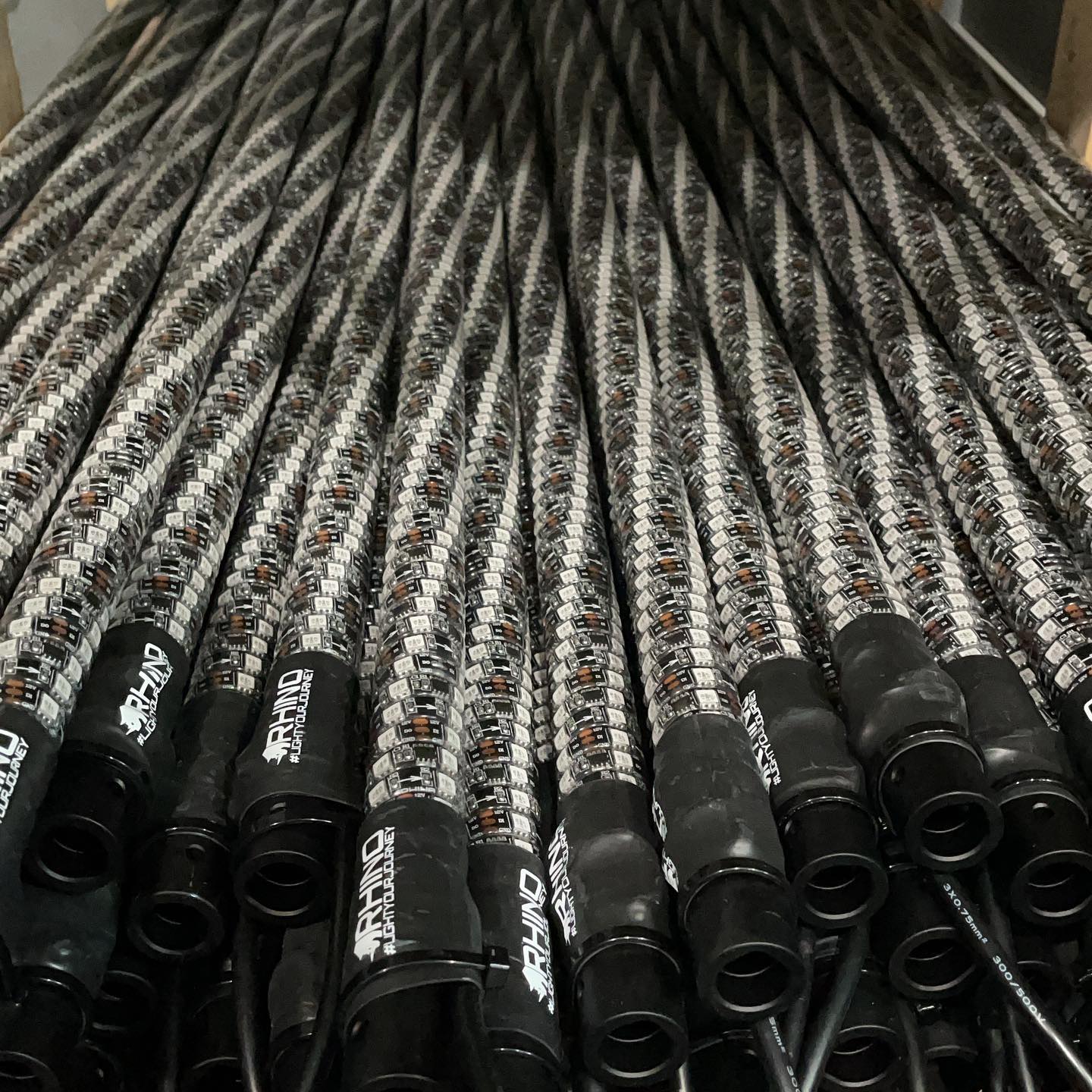 A dense row of finished Rhino whips on the bench, machined bases forward